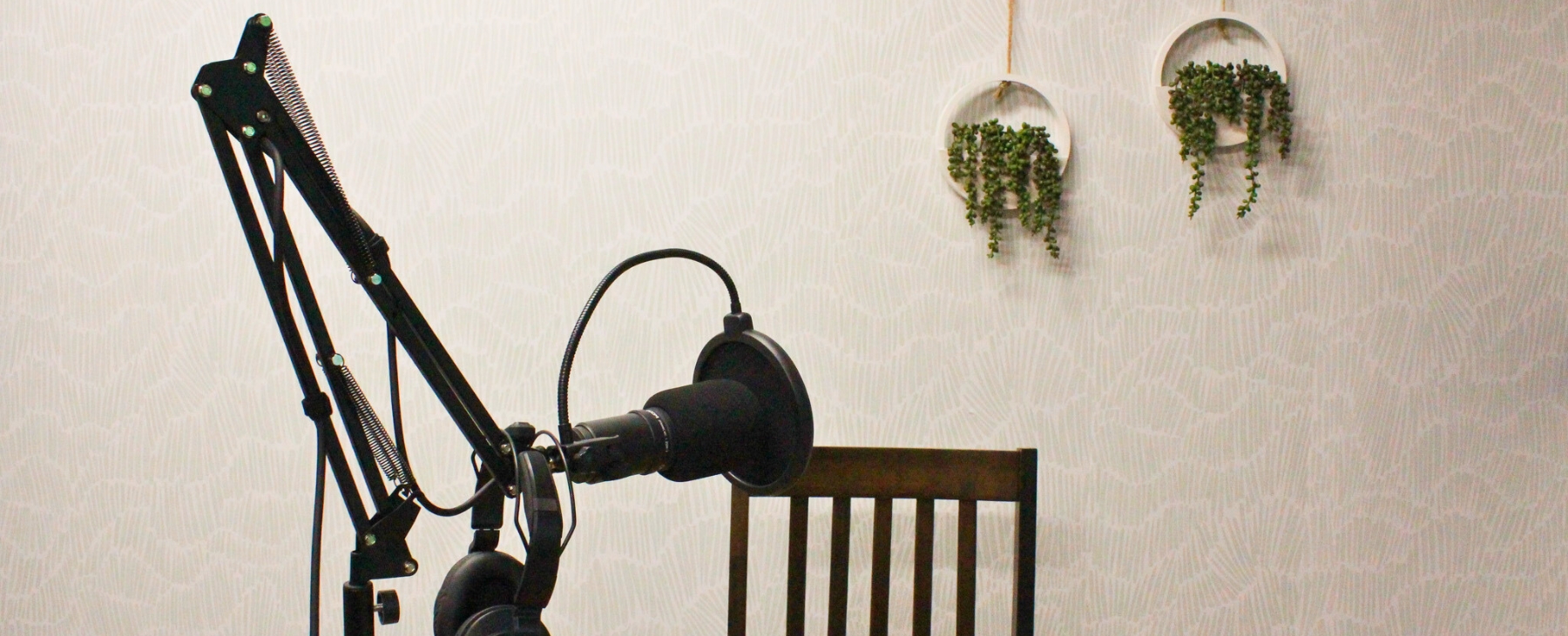 recording space with microphone and patterned wall paper with plants mounted on the right of the wall